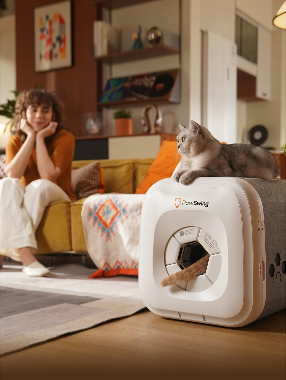 A cat resting on a PawSwing® neo self grooming cat house while another cat’s tail peeks from inside