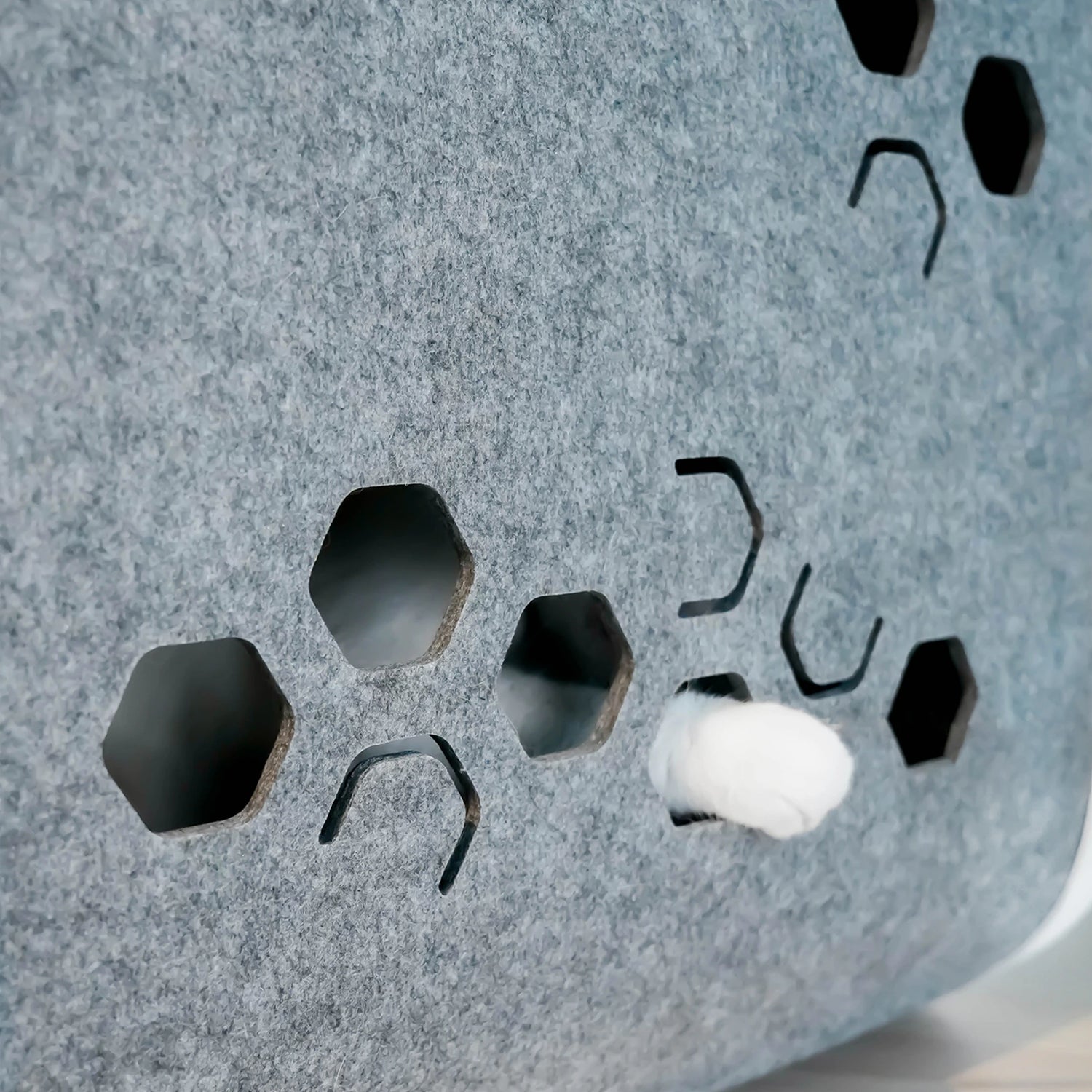A cat's paw playfully pokes through the textured side of a PawSwing® neo self grooming cat house