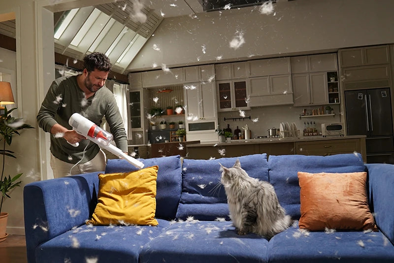 Man vacuuming fur near a cat, highlighting the need for a PawSwing® neo grooming brush for cat